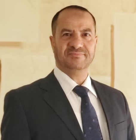 Professional headshot of a man wearing a black suit